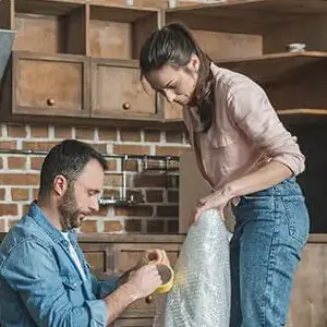 Man and woman packing item in bubble wrap.