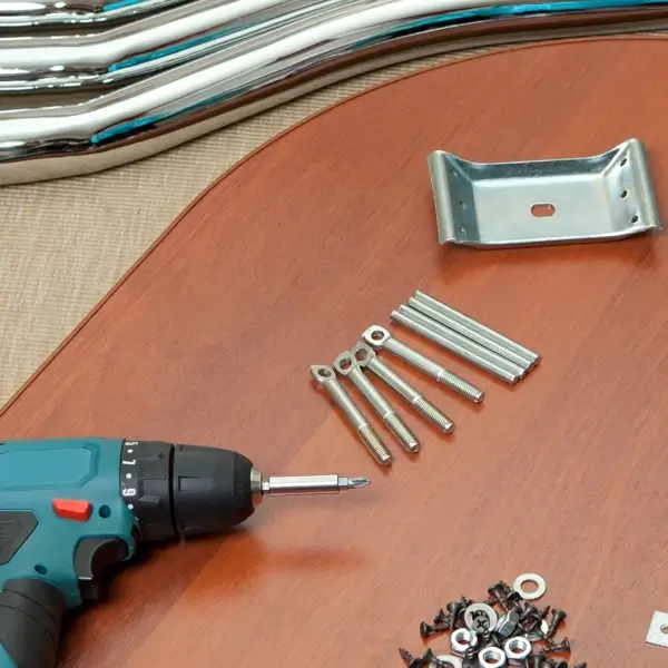 Electric drill and hardware on wooden table.
