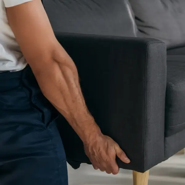 Man gripping sofa arm, visible hand veins.