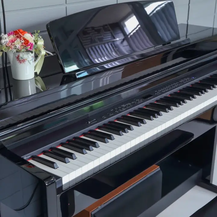 Glossy black digital piano with floral arrangement.
