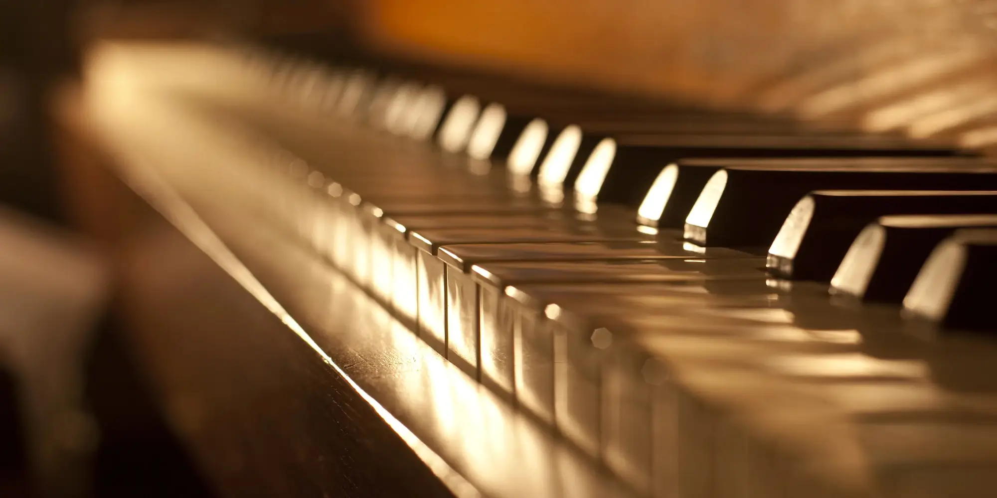 Close-up of piano keys with golden lighting.